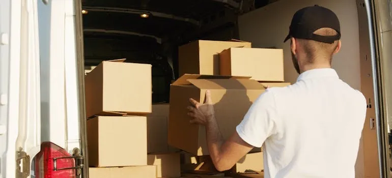 A mover loading boxes onto a moving vehicle while using weight distribution techniques for safer moves